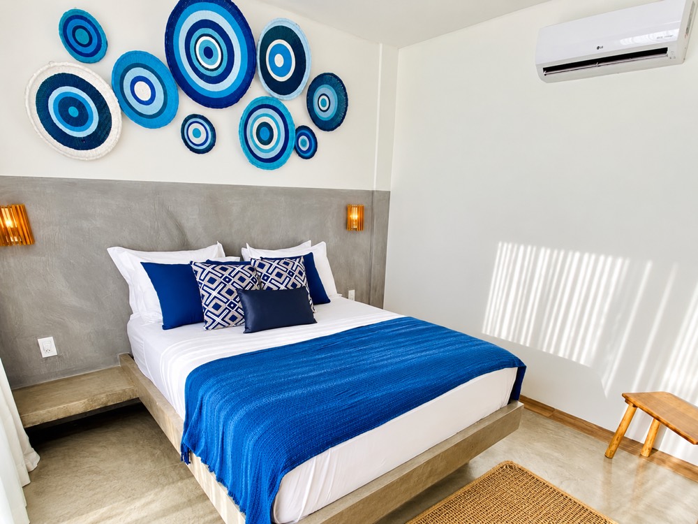 Private room with a double bed, blue throw and woven wall art