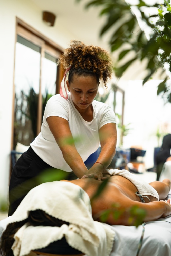 A therapist giving a sports massage in a shaded garden