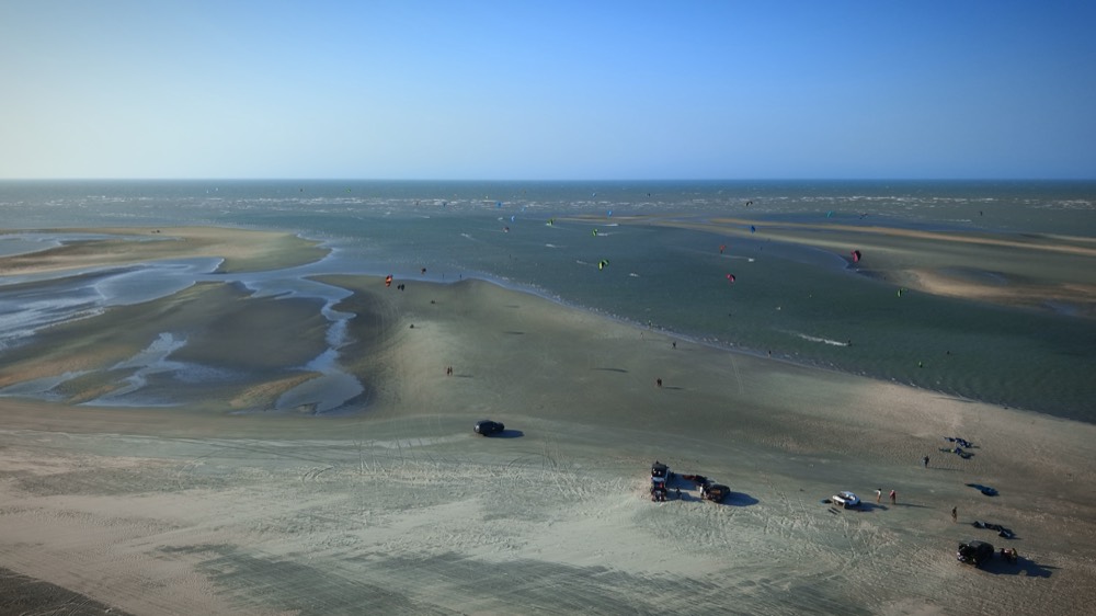 Aerial view of the Guriú sandbanks with 4x4s parked and kiters on the water