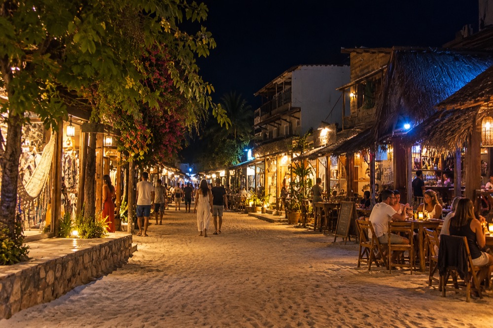 Jericoacoara's sand streets at night, lined with lit restaurants and people walking