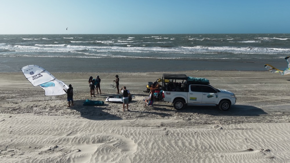 Drone view of the crew's 4x4 pickup on the beach with kites ready to launch